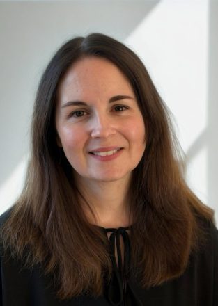 A photo of Mel wearing a black top, smiling at the camera.